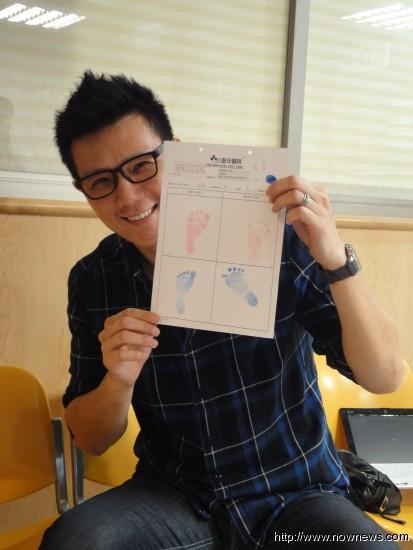 蒋伟文看着儿子的脚印，忧心他会跟自己一样「大手大脚」，但脸上满是幸福。（记者许世颖／摄影）